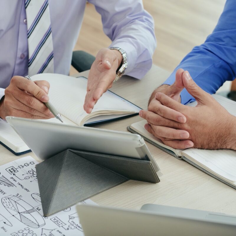 Close-up image of coworkers discussing data on tablet computer screen